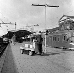 857764 Afbeelding van een stationsassistent met een elektrokar met expresgoed op het eerste perron van het N.S.-station ...